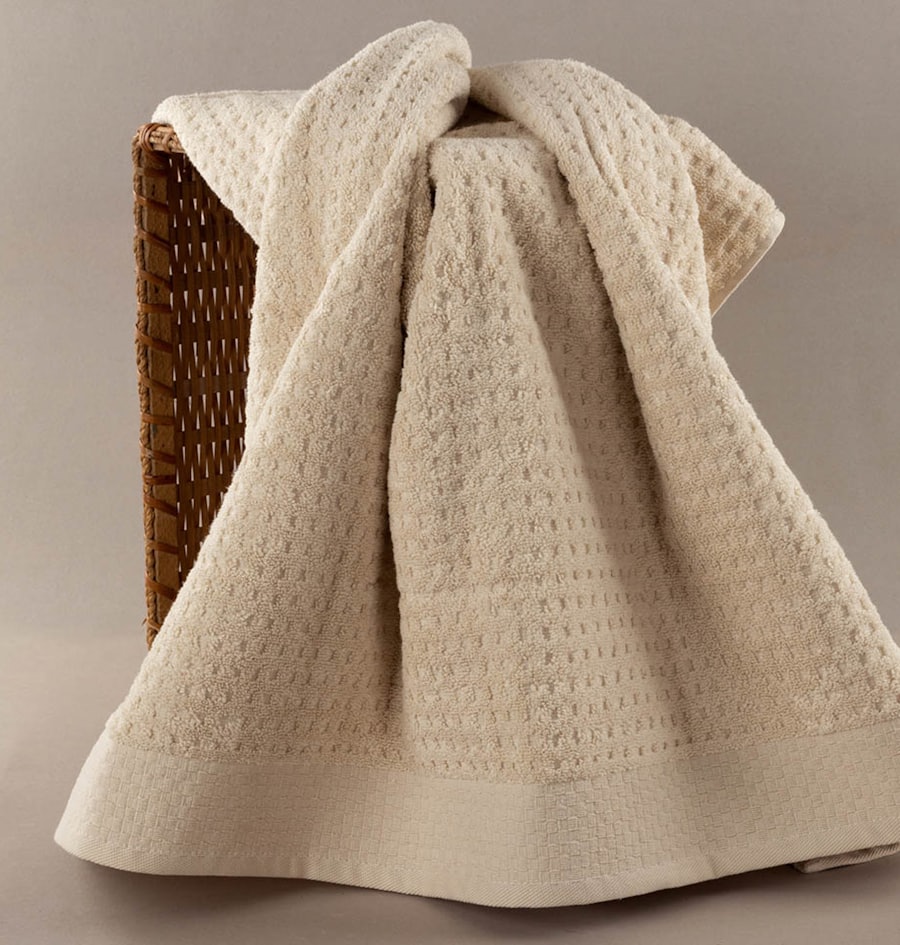 Soft cream towels folded over a woven basket
